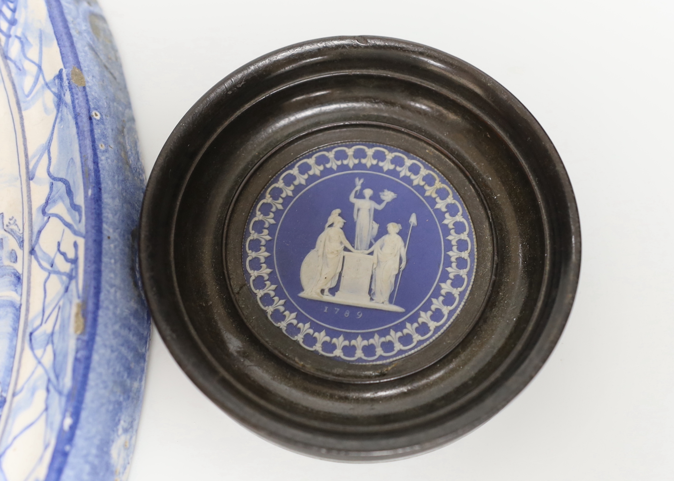 A framed Wedgwood jasperware circular plaque dated 1789 and a delft blue and white example, the largest 37cm high